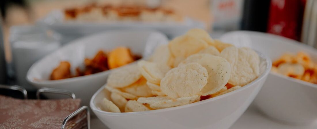A variety of chips served in white bowls on a table, perfect for party snacks.