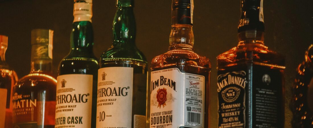A selection of premium whiskey brands elegantly arranged on a dimly lit display shelf.